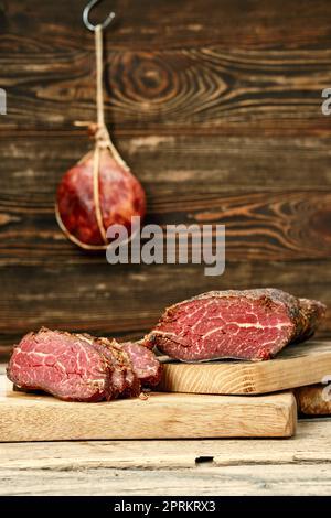 Viande de bœuf fumée séchée coupée sur des tranches sur une planche à découper en bois Banque D'Images