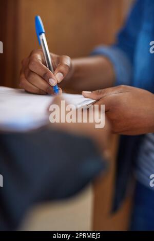 Signature sur la ligne pointillée. Une femme non reconnaissable signe pour une livraison. Banque D'Images