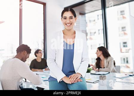 Je garde tout le monde au travail et à aller de l'avant. Portrait d'une femme d'affaires dans un bureau avec ses collègues en arrière-plan. Banque D'Images