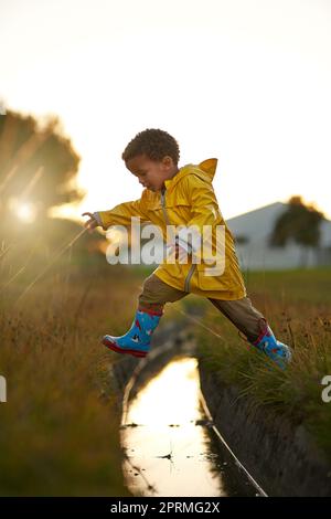 Un saut géant pour le boykind. Un petit garçon sautant sur l'eau en jouant à l'extérieur. Banque D'Images