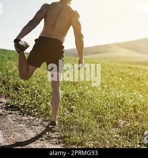 HES ne tire aucun muscle aujourd'hui. Vue arrière d'un jeune homme qui s'étire à l'extérieur avant une course. Banque D'Images