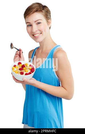 Je m'aime une cuillerée de bonheur. Portrait studio d'une jeune femme qui apprécie un muesli et un yogourt. Banque D'Images