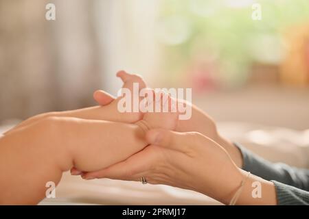 Vous êtes aimés, un peu. Une mère non identifiable tenant ses pieds de bababs. Banque D'Images