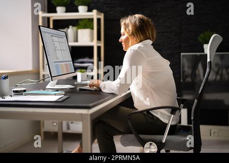 Femme assise dans une mauvaise posture travaillant sur un ordinateur Banque D'Images