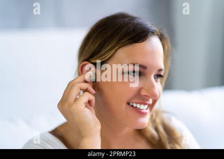 Femme utilisant des bouchons d'oreilles Banque D'Images