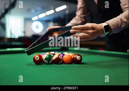 Homme mettant des boules de billard dans un rack triangulaire Banque D'Images