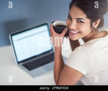 Juste un petit café pour me garder. Portrait en grand angle d'une jeune femme d'affaires qui boit du café tout en travaillant sur un ordinateur portable dans son bureau. Banque D'Images