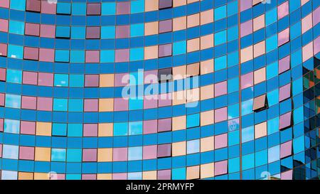 La façade en verre d'un bâtiment moderne. Réflexions multicolores dans les fenêtres. Carrés et lignes. Image d'arrière-plan abstraite géométrique Banque D'Images