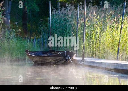 Un bateau à rames en bois qui se trouve à côté d'un pont à la lumière du matin Banque D'Images