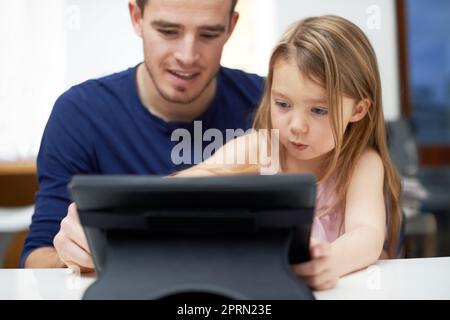 Shes techno-savvy pour son âge. Une jeune fille utilisant la technologie sous la supervision de son père. Banque D'Images