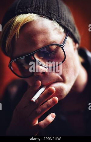 Prendre un glissement. Un jeune homme en ville allume une cigarette Banque D'Images