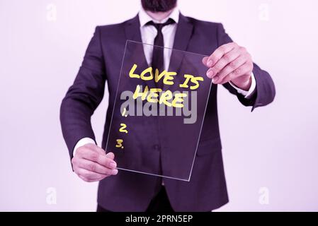 Légende de texte présentant l'amour est ici, mot écrit sur le sentiment romantique agréable émotion expression positive Care Joy Banque D'Images