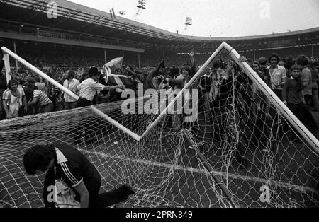 Photo du dossier en date du 04-06-1977 d'Un poteau de but a été écrasé et déchiré alors qu'un policier a essayé de calmer certains des milliers de fans écossais en train de courir sauvage sur le terrain au stade de Wembley après la défaite de l'Écosse contre l'Angleterre en 2-1. Date de publication : jeudi 27 avril 2023. Banque D'Images