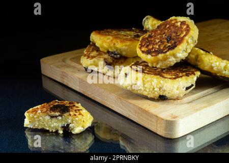Fromage cottage frit avec raisins secs sur une table en verre. Nourriture sur fond noir Banque D'Images