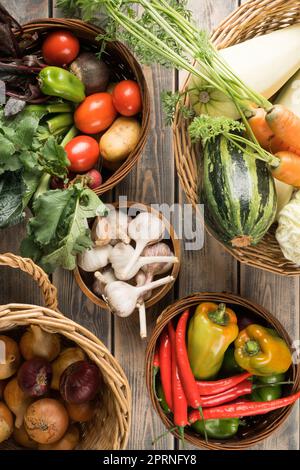 Paniers en osier avec différents légumes frais du jardin sur une table en bois, vue sur le dessus. Bols pleins de récolte biologique mûre. Concept d'alimentation ou d'alimentation saine. Nit Banque D'Images