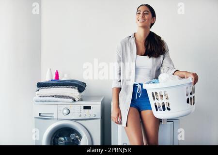 Il y a quelque chose de magique à glisser dans des vêtements frais odorants. une jeune femme attirante faisant sa lessive à la maison. Banque D'Images