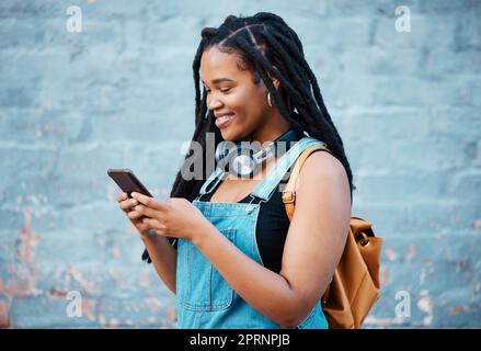 Femme noire, sourire et téléphone d'un étudiant de Jamaïque avec technologie et écouteurs. Heureux, urbain et personne de génération z utilisant 5g Internet, Web et social Banque D'Images