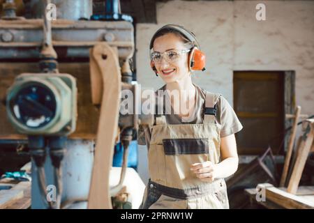 Femme charpentier dans la menuiserie traditionnelle en ajustant la machine de rabot par main Banque D'Images