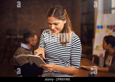 Préparer sa présentation sur sa tablette. Une jeune femme d'affaires assise dans la salle de conférence. Banque D'Images