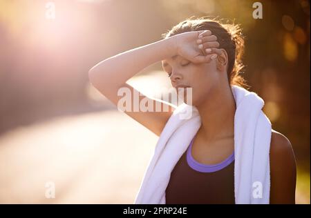 De bonnes choses viennent à ceux qui suent. Une femme essuyant la sueur après un entraînement intense en plein air. Banque D'Images