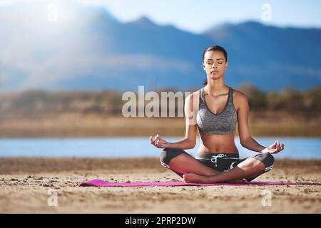 Vous créez votre propre calme. Une jeune femme pratiquant le yoga en plein air. Banque D'Images