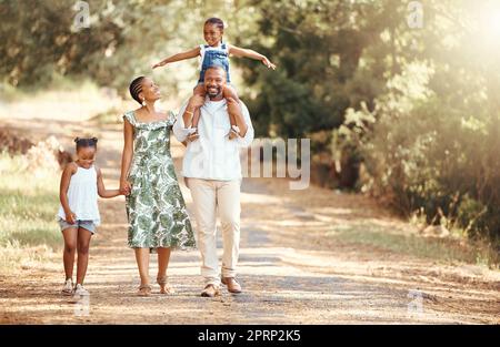 Bonne famille noire se liant sur un travail extérieur dans un parc, aimant et s'amuser ensemble. Parents Afro-américains appréciant l'air frais et une marche active avec leurs enfants, ludique, gai et gratuit Banque D'Images