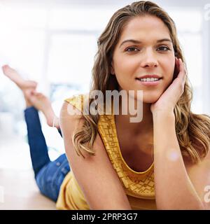 Aujourd'hui, il s'agit de se dérouler. Portrait d'une jeune femme couché sur le sol de son salon Banque D'Images