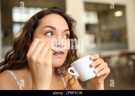 Femme buvant du café avec une cuillère dans un bar Banque D'Images