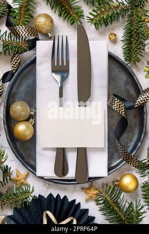 Table de Noël noire et dorée avec carte de placement, ornements et branches de sapin. Maquette Banque D'Images