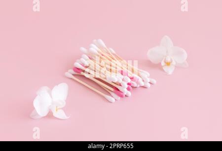 Boutons de coton bambou près des fleurs d'orchidées blanches sur rose clair, maquette. Produit de soin de la peau Banque D'Images