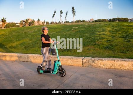 Active jeune à coeur 60s Dame/femme utilisant un scooter électrique sur la promenade à tel Aviv Israël Banque D'Images