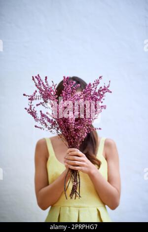 Où êtes-vous allé ? Portrait studio d'une femme méconnaissable tenant un bouquet de fleurs debout sur fond gris Banque D'Images