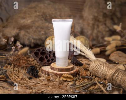 Tube de crème en plastique blanc sur bois près des décorations naturelles closeup. Maquette d'emballage cosmétique Banque D'Images