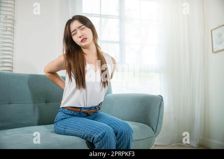 Femme asiatique tenant son bas du dos se sentant douloureuse massage de la taille Banque D'Images