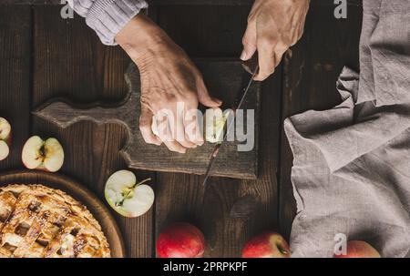 Femme coupant des pommes pour la tarte sur une table en bois brun Banque D'Images