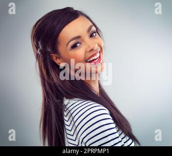 Shes heureux-Go-chanceux. Photo en studio d'une jeune femme posant sur un fond gris Banque D'Images