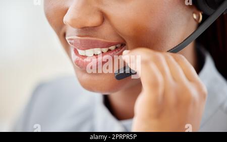 Femme de service à la clientèle, parler la bouche et sourire avec un micro-casque dans un bureau de télémarketing ou de centre d'appels. Consultant afro-américain travaillant dans un service d'assistance ou un travail d'assistance tout en consultant un client Banque D'Images