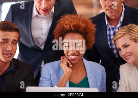 Le travail d'équipe fait le travail de rêve. Un groupe d'hommes d'affaires se réunissait autour d'un seul ordinateur portable. Banque D'Images