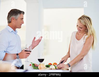 Un couple d'âge mûr qui parle ensemble tout en faisant le dîner Banque D'Images