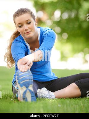 Elle s'étire toujours. Jeune coureur attrayant s'étirant avant une course Banque D'Images