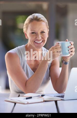 Du café pour continuer. Portrait rogné d'une femme d'affaires attirante travaillant sur son ordinateur portable Banque D'Images