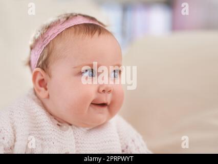 Shes un si curieux petit. Une adorable petite fille de bébé regardant sur le côté. Banque D'Images