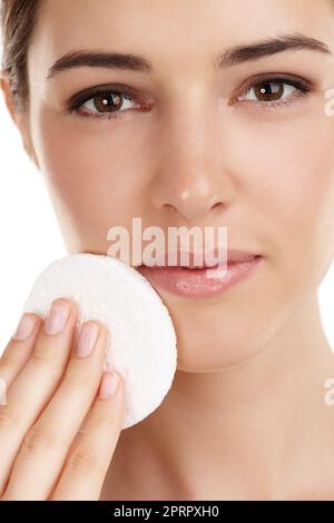 Une peau parfaite prend du temps. Portrait court d'une belle jeune femme exfoliant son visage sur un fond blanc Banque D'Images