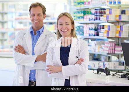 Travailler main dans la main avec les médecins pour assurer votre santé. Portrait de deux pharmaciens debout au comptoir d'ordonnance Banque D'Images