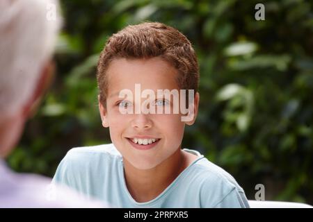 HES un grand enfant. Portrait d'un petit garçon heureux assis avec sa famille à l'extérieur. Banque D'Images