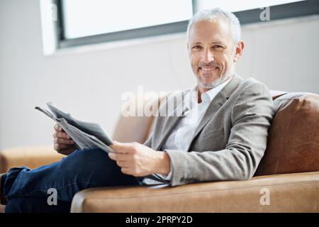 Détendez-vous avec les dernières nouvelles. Portrait d'un beau homme mature se reposant avec le journal à la maison Banque D'Images