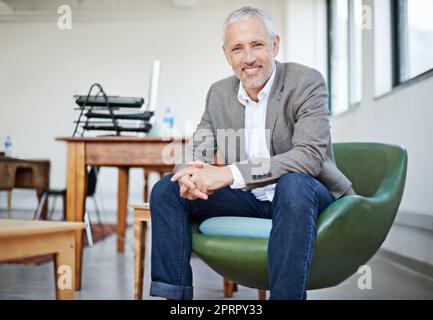 Cool, calme et recueilli. Portrait d'un homme d'affaires mature assis dans une chaise dans un bureau Banque D'Images