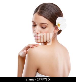 Une beauté élégante. Studio photo d'une belle jeune femme avec une orchidée dans ses cheveux regardant au-dessus de son épaule Banque D'Images