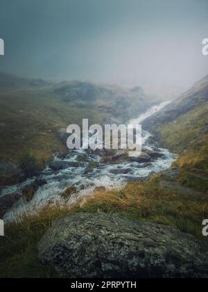 Ruisseau de montagne qui coule rapidement à travers une vallée rocheuse dans les montagnes Fagaras. Rivière avec débit d'eau élevé pendant la saison des pluies Banque D'Images