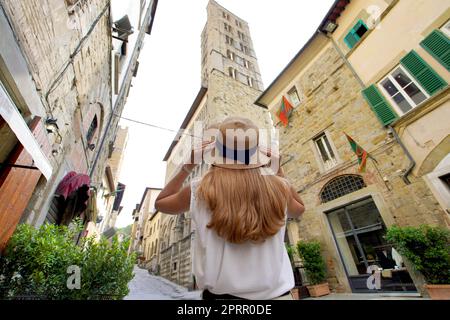 Belle fille touristique tient chapeau marchant dans la ville du Moyen âge d'Arezzo, Toscane, Italie. Angle bas. Banque D'Images